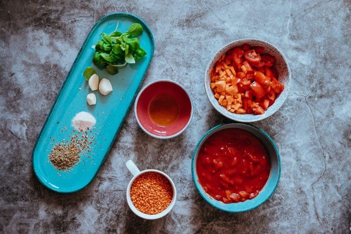 Ingrediencie na omáčku z červenej šošovice – strukoviny spolu s nakrájanými paradajkami, mrkvou a koreninami.