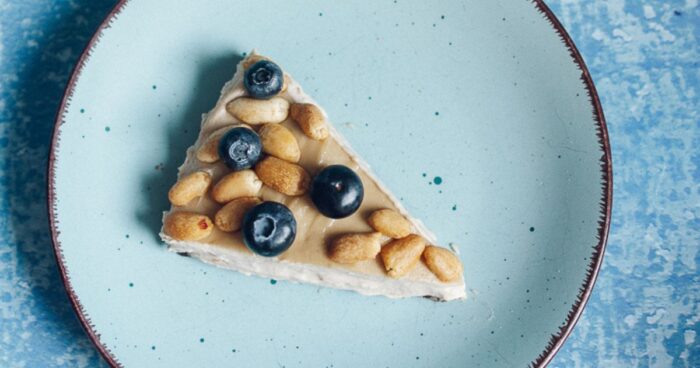 Nepečený cheesecake ozdobte ovocím a arašidy.