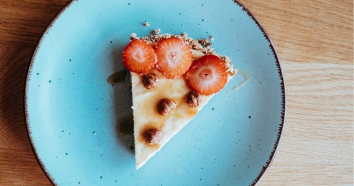 Ozdobte cheesecake plátkami čerstvých jahôd, ktoré mu dodajú sviežosť a farbu, doplnené chrumkavými nasekanými lieskovými orieškami, ktoré zabezpečia harmóniu textúr a bohatú orechovú chuť.